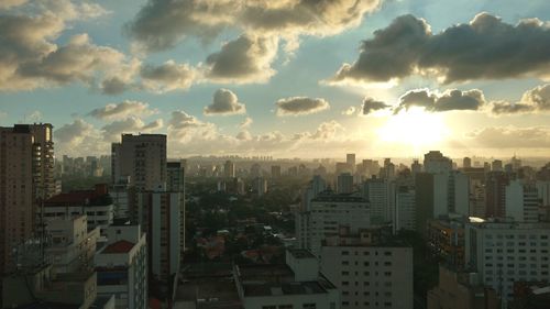 Aerial view of city buildings against sky during sunset