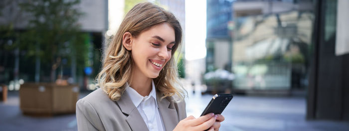 Portrait of young woman using mobile phone in cafe