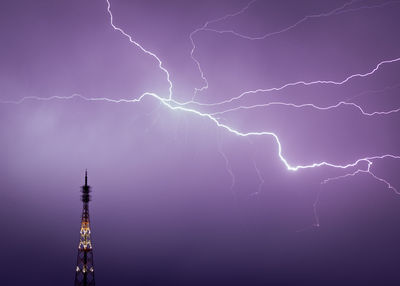 Low angle view of lightning over tower at night