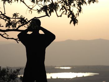 Silhouette woman by sea against sky during sunset