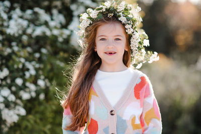 Happy smiling kid girl 6-7 year old wear knit colorful sweater wreath hairstyle with flowers