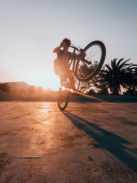 Low angle view of man performing stunt on bicycle on footpath
