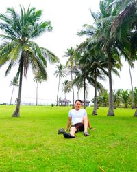 Young woman sitting on palm tree