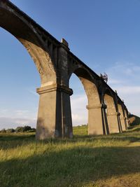 Low angle view of arch bridge on field against sky