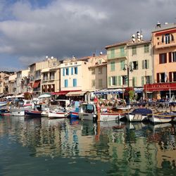 Boats moored in canal by buildings against sky