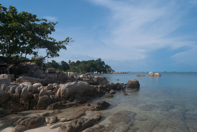 Rock formations on coast against cloudy sky