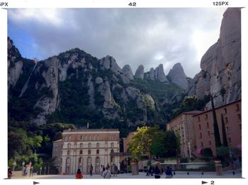 Tourists on mountain against cloudy sky
