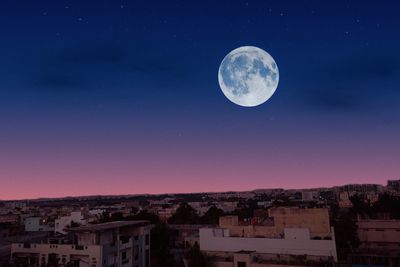 Scenic view of moon in city against sky at night