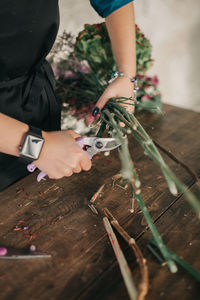 Young woman working in flower shop and making bouquet for customer