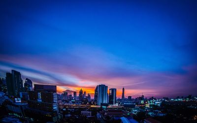 Illuminated buildings in city against sky during sunset