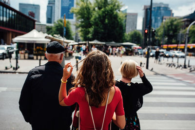 Rear view of people walking on road in city