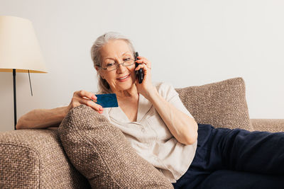 Young woman using phone while sitting on sofa at home