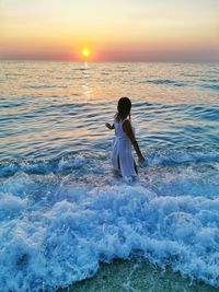 Woman on beach against sky during sunset