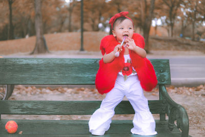 Full length of cute baby girl standing on bench in park