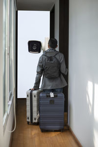 Rear view of man with luggage standing in corridor