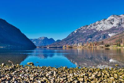 Scenic view of lake and mountains against blue sky