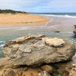 Rock formation on beach against sky