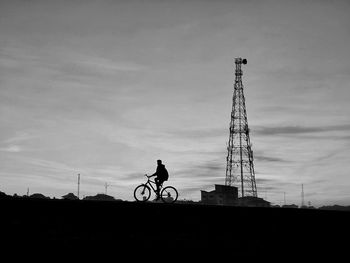 Low angle view of silhouette man riding bicycle against sky