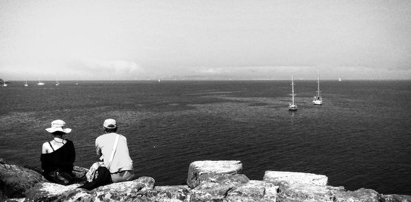 Man sitting on sea against sky