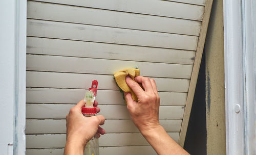 Cropped image of person holding hands against white wall