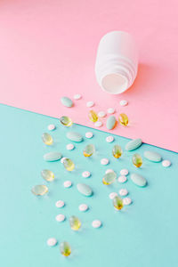 Close-up of pills spilling from bottle against blue background