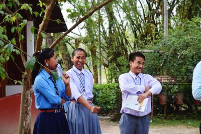 Students smiling while standing against trees