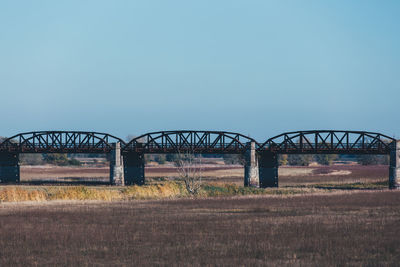 Arch bridge on field against clear sky