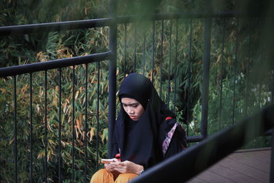 Young woman looking at camera while sitting by plants