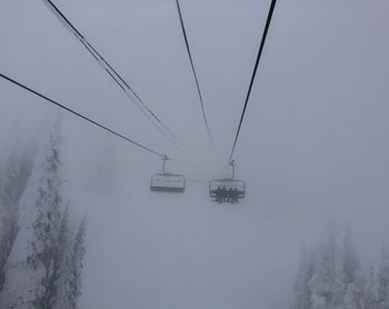 Ski lift over snow covered mountains against sky
