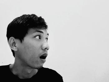 Portrait of young man looking away against white background