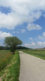 Road amidst field against sky