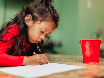 Close-up of girl looking away while sitting on table