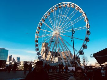 Low angle view of ferris wheel against blue sky