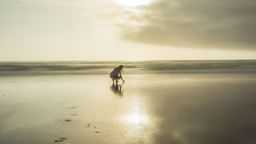 Side view of woman crouching at beach