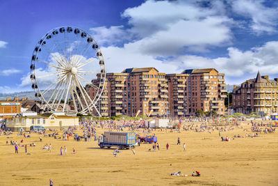 Ferris wheel at beach against sky in city