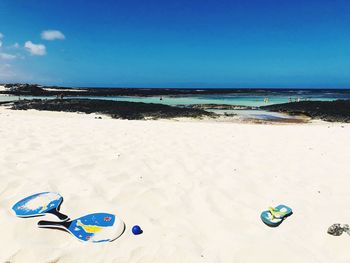 Deck chairs on beach against blue sky