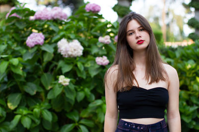Portrait of a beautiful young woman standing against white flowering plants