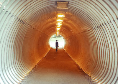 Rear view of man walking in tunnel