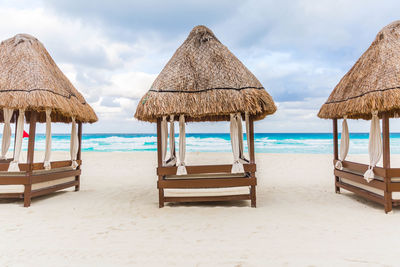 Deck chairs on beach against sky