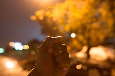 Close-up of human hand against sky at night