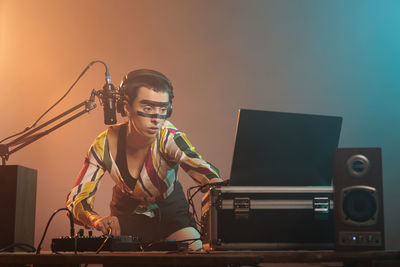 Portrait of young man using mobile phone while sitting on stage