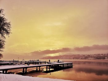 Pier over lake against sky during sunset