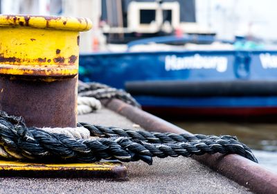 Close-up of rope tied to bollard at harbor