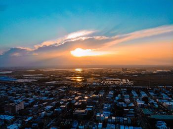 High angle view of townscape by sea against sky during sunset