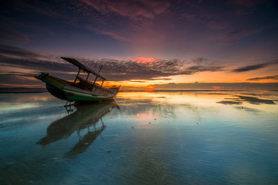 Fishing boat in sea against sky during sunset