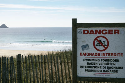 Information sign on beach against sky