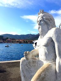 Statue by sea against sky