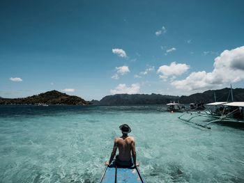 Rear view of shirtless man on sea against sky