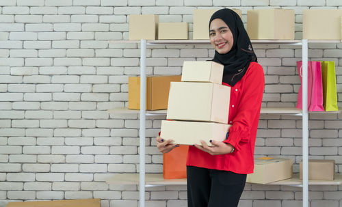 Portrait of a smiling young woman standing against brick wall