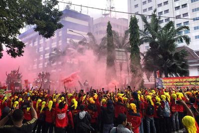 Crowd with red distress flare on street in city during labor day